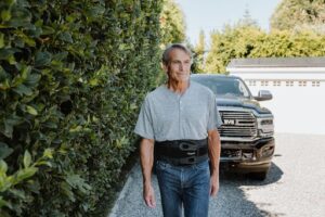 A man wearing the Horizon back brace walking away from his car after running errands.