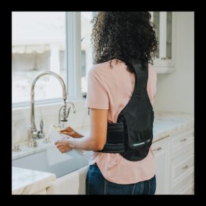 A woman using the Horizon Pro back brace while doing chores around the house.